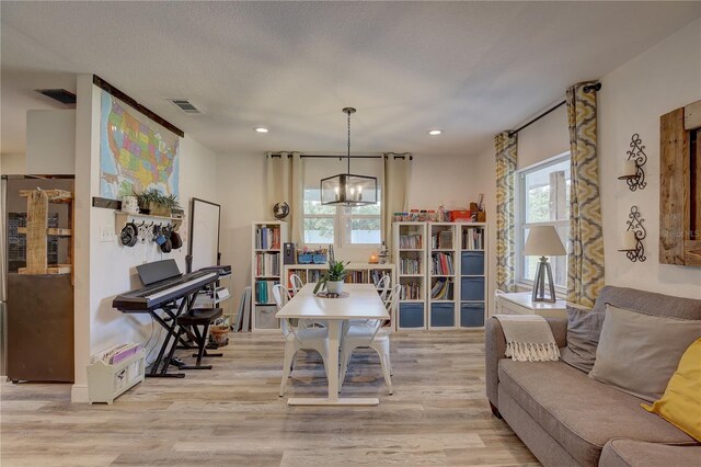 living room featuring light hardwood / wood-style flooring, a chandelier, and a textured ceiling