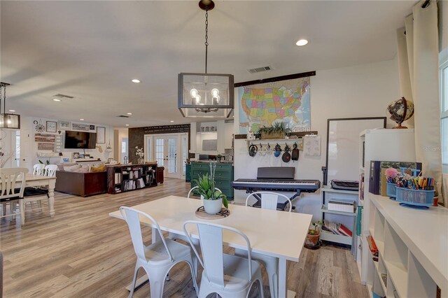 dining room with light wood-type flooring and a chandelier