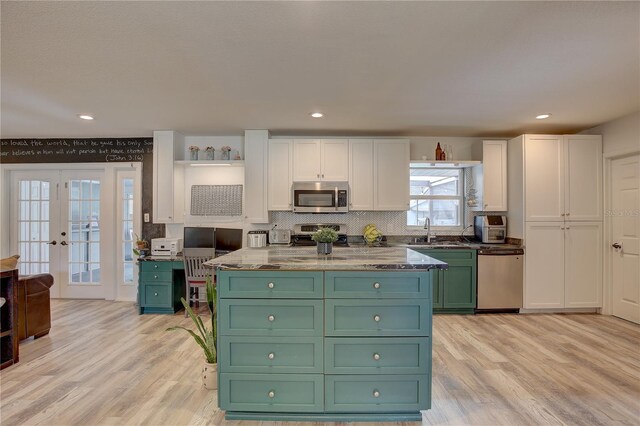 kitchen with light wood-type flooring, sink, white cabinetry, stainless steel appliances, and french doors