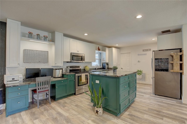 kitchen featuring appliances with stainless steel finishes, light hardwood / wood-style floors, white cabinetry, and a center island