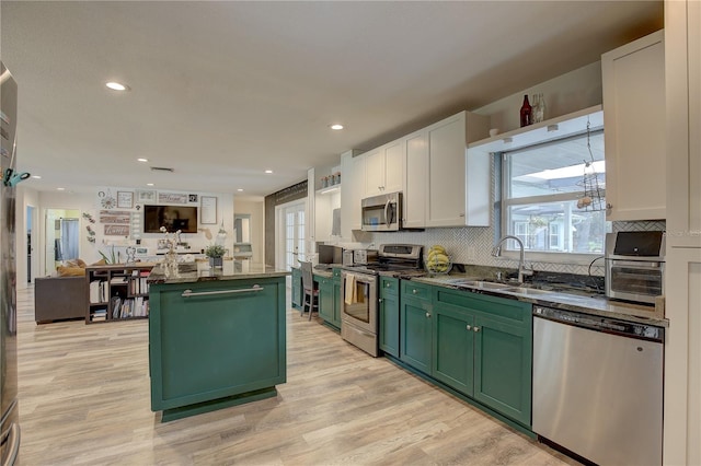 kitchen with sink, a kitchen island, white cabinetry, stainless steel appliances, and green cabinets