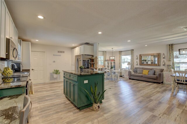 kitchen with appliances with stainless steel finishes, white cabinetry, a kitchen island, and plenty of natural light