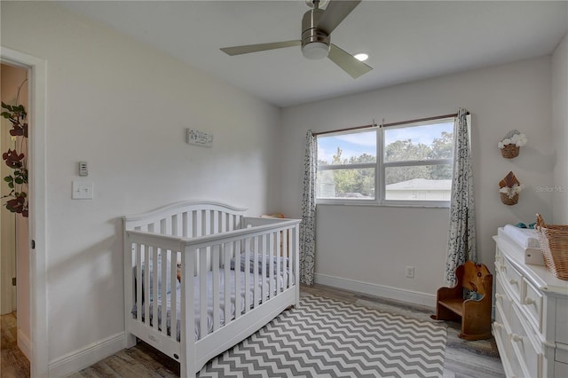 bedroom featuring light hardwood / wood-style floors, ceiling fan, and a crib