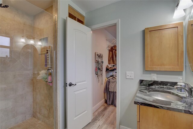 bathroom with hardwood / wood-style flooring, walk in shower, and vanity