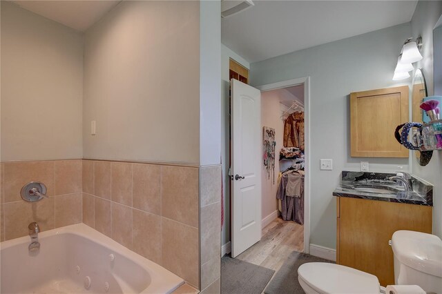 bathroom with a bathtub, wood-type flooring, vanity, and toilet