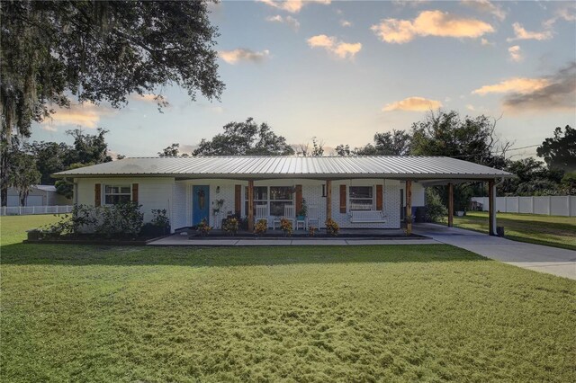 ranch-style house featuring covered porch and a yard