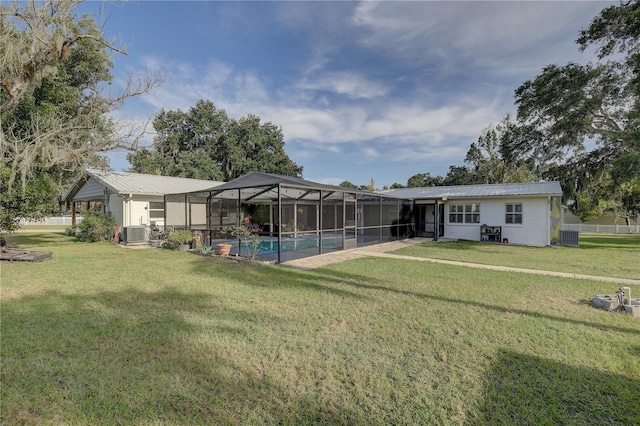 rear view of property with a yard, a lanai, and central AC