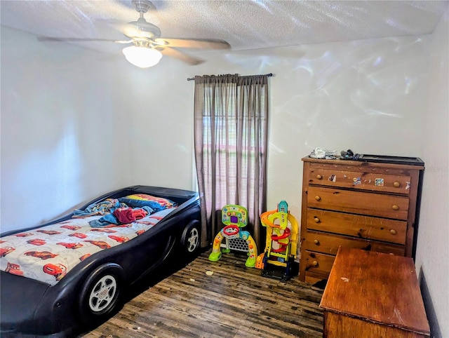 bedroom with a textured ceiling, ceiling fan, and dark hardwood / wood-style flooring