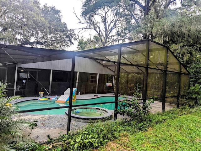 view of pool featuring glass enclosure, an in ground hot tub, and a patio