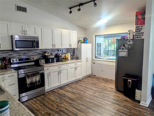 kitchen featuring white cabinets, appliances with stainless steel finishes, lofted ceiling, dark wood-type flooring, and a textured ceiling