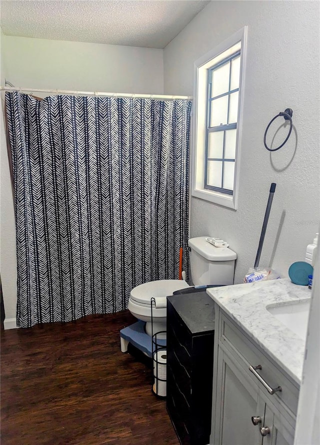 bathroom with a textured ceiling, vanity, curtained shower, wood-type flooring, and toilet