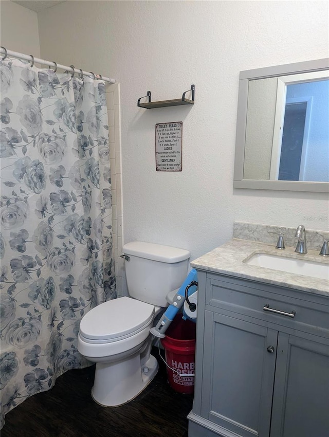 bathroom featuring walk in shower, vanity, toilet, and hardwood / wood-style floors