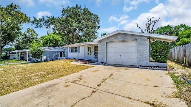 view of front of house with concrete driveway, fence, a garage, stone siding, and a front lawn