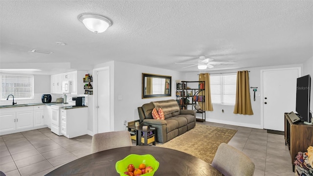 living room with tile patterned flooring, ceiling fan, and a textured ceiling