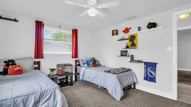 carpeted bedroom featuring a ceiling fan, visible vents, and baseboards