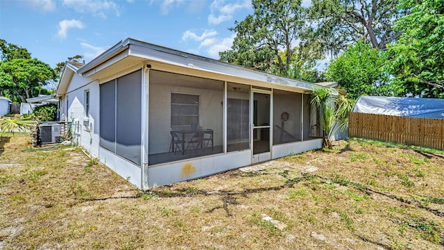 rear view of house with a lawn, fence, a sunroom, and central air condition unit