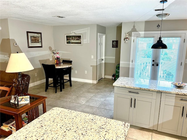 kitchen featuring decorative light fixtures, light tile patterned flooring, light stone countertops, and a textured ceiling