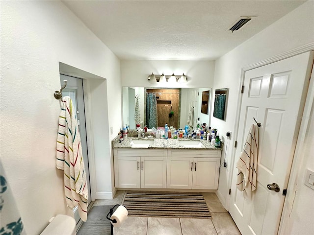 bathroom with tile patterned flooring, vanity, a textured ceiling, and walk in shower