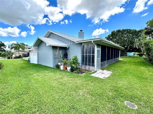 rear view of property with a sunroom and a lawn