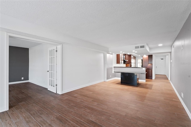 unfurnished living room with a textured ceiling and hardwood / wood-style flooring