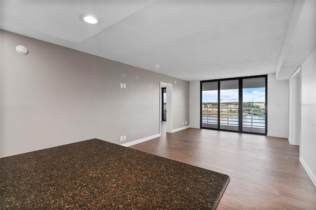 interior space with wood-type flooring, a textured ceiling, and a wall of windows