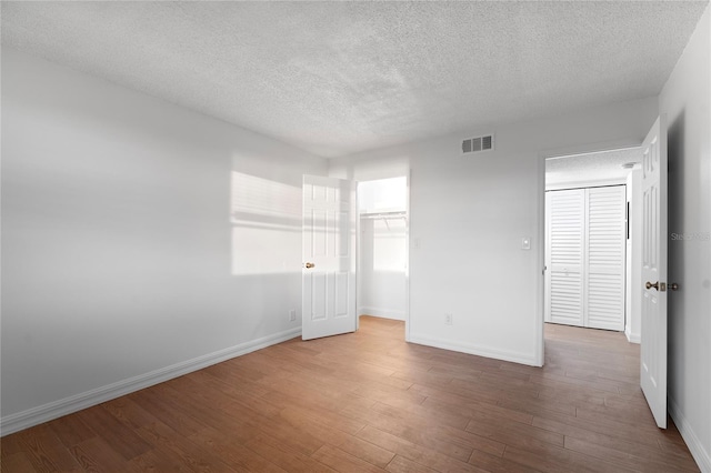 unfurnished bedroom with wood-type flooring, a closet, and a textured ceiling