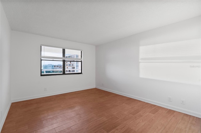 empty room with wood-type flooring and a textured ceiling