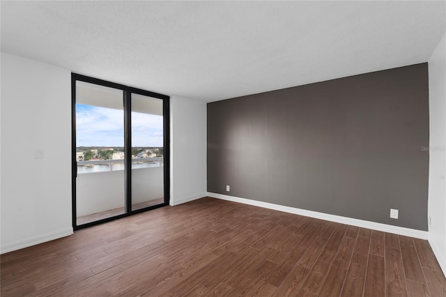 spare room with expansive windows, hardwood / wood-style flooring, and a textured ceiling