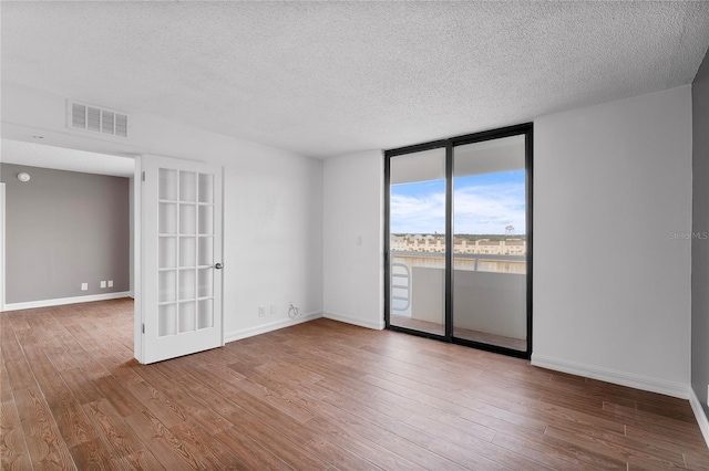 empty room with floor to ceiling windows, a textured ceiling, and hardwood / wood-style floors