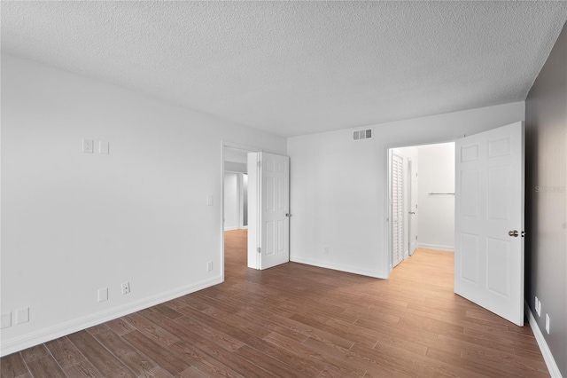 spare room with a textured ceiling and hardwood / wood-style flooring