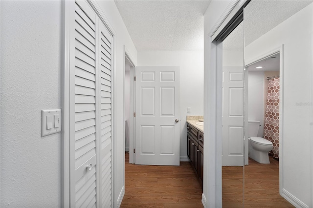 bathroom with a textured ceiling, hardwood / wood-style flooring, a shower with curtain, vanity, and toilet