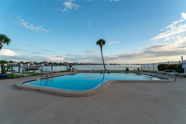 view of swimming pool featuring a patio and a water view