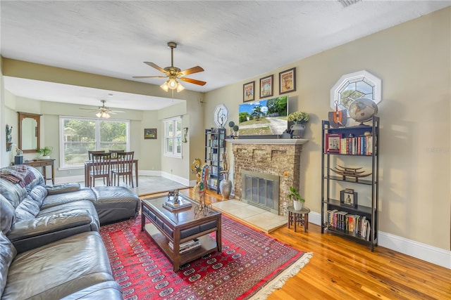 living room featuring wood-type flooring, ceiling fan, and a textured ceiling