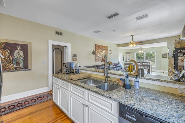 kitchen with white cabinets, sink, stone counters, stainless steel dishwasher, and light hardwood / wood-style flooring