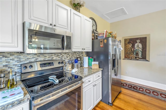 kitchen featuring light hardwood / wood-style floors, white cabinetry, light stone counters, appliances with stainless steel finishes, and tasteful backsplash