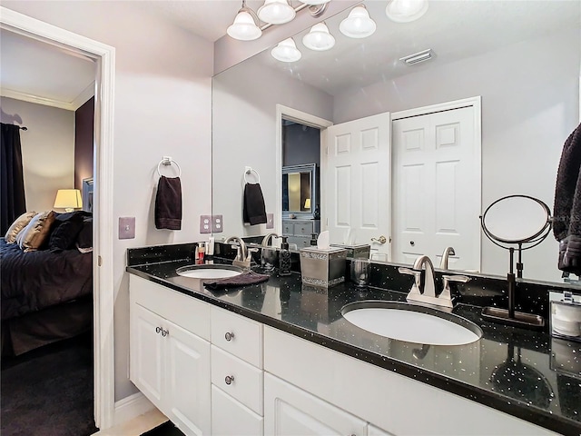 ensuite bathroom with double vanity, connected bathroom, visible vents, and a sink