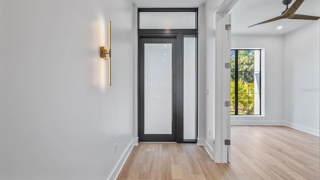 doorway featuring light wood-style floors, plenty of natural light, and baseboards