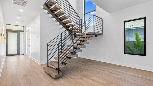 stairs featuring a healthy amount of sunlight, visible vents, baseboards, and wood finished floors