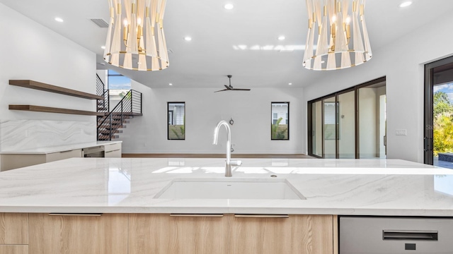 kitchen with modern cabinets, light stone counters, open floor plan, and a sink