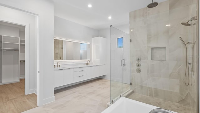 bathroom featuring a walk in closet, recessed lighting, a bathing tub, a stall shower, and vanity