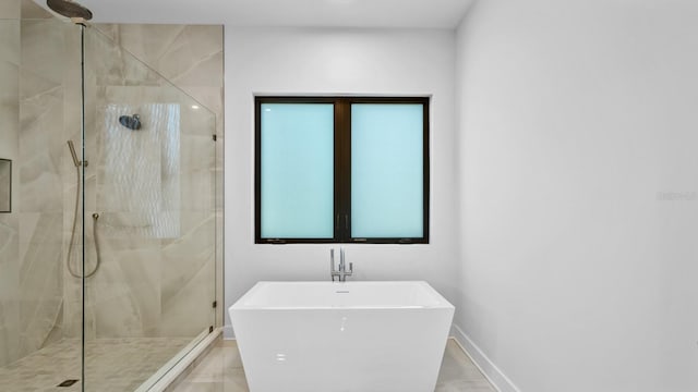 bathroom with a freestanding tub, a sink, a shower stall, and baseboards