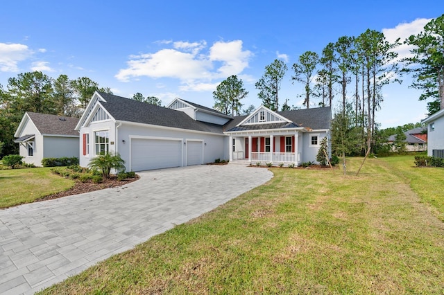 view of front of house featuring covered porch, a front yard, and a garage