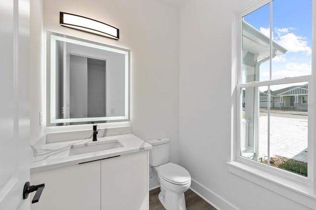 bathroom featuring vanity, hardwood / wood-style flooring, toilet, and a wealth of natural light