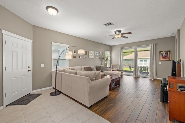 living room featuring ceiling fan, a textured ceiling, and light wood-type flooring