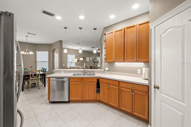 kitchen featuring sink, decorative light fixtures, light tile patterned floors, appliances with stainless steel finishes, and kitchen peninsula