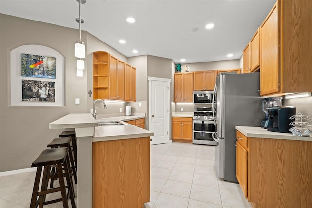 kitchen with sink, a breakfast bar area, decorative light fixtures, kitchen peninsula, and stainless steel appliances