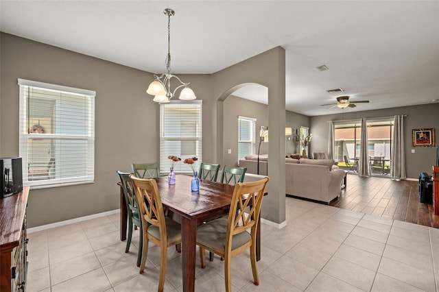 tiled dining room featuring ceiling fan with notable chandelier