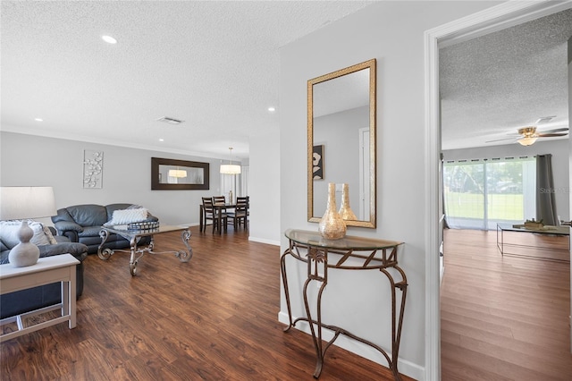 living room with dark hardwood / wood-style flooring, a textured ceiling, crown molding, and ceiling fan