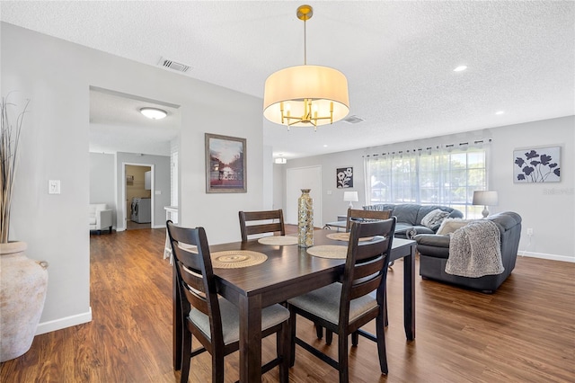 dining space with a textured ceiling, a chandelier, and dark hardwood / wood-style floors