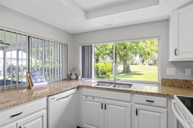 kitchen featuring a textured ceiling, dishwasher, and a healthy amount of sunlight